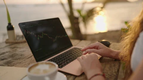 Female cryptocurrency trader at laptop checking candlestick charts online Stock Footage 234809428