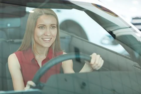 Female customer behind windscreen testing car in car saloon Stock Photos