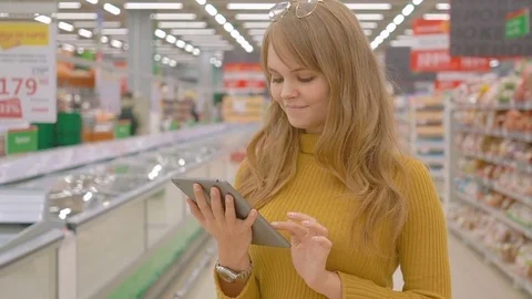 Female customer checking grocery list in supermarket Stock Footage 75346438