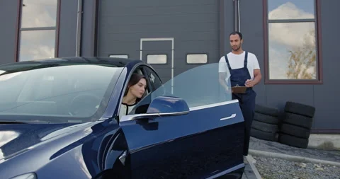 Female Customer Discussing Car Issues with Mechanic Outside Workshop Stock Footage 276616244