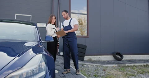 Female Customer Discussing Car Problem with Automotive Technician Outside Stock Footage 276616670
