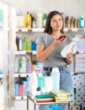 Female customer scanning barcode on disinfectant spray for discounts in store Stock Photos