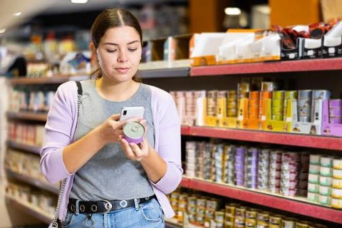 Female customer scanning barcode on tin can of canned food in pet store Stock Photos