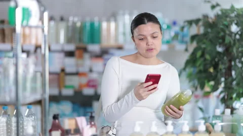 Female customer scanning QR code on bottle on shampoo in store Stock Footage 318434471