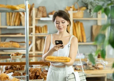 Female customer scanning QR code on label of fresh baked goods in bakery Stock-Fotos