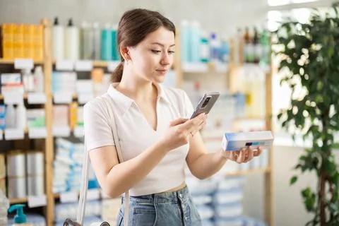 Female customer scanning QR code on box of ointment in pharmacy Foto stock