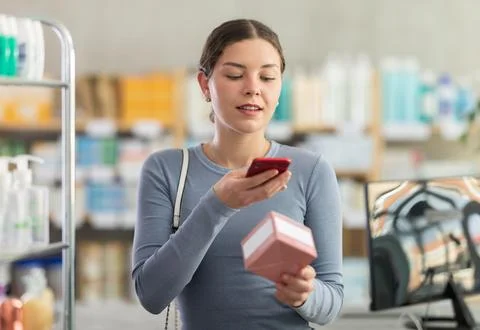 Female customer scanning QR code on pills with phone in drugstore Foto stock
