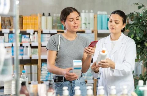 Female customer scanning QR code on body cream at pharmacy Stock-Fotos