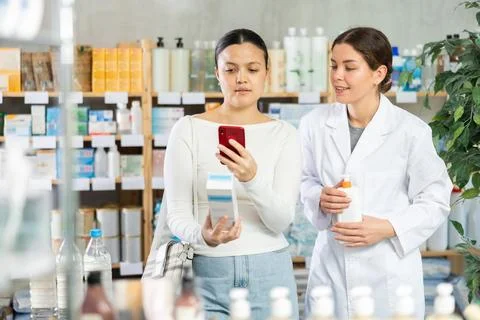 Female customer scanning QR code on body cream at pharmacy Stock-Fotos