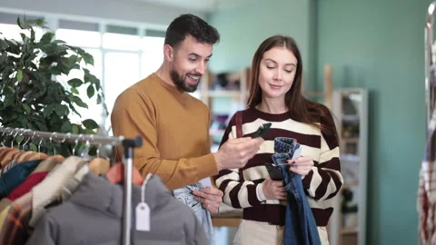 Female customer scans QR code on jeans label, man help Stock Footage 331315167
