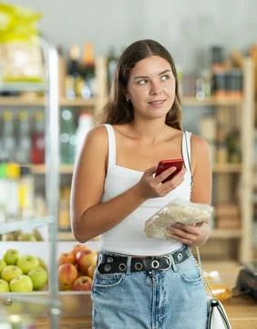 Female customer scans QR code on label oat flakes using smartphone. Checking Stock-Fotos