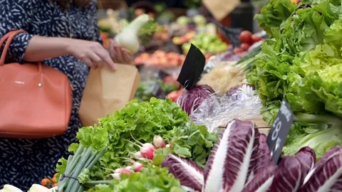 A female customer selecting vegetables at a fruit and veg stall at Borough Ma Stock Footage 120637474