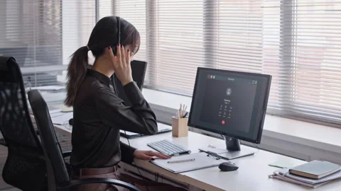Female Customer Service Specialist Using Headset and Calling on Computer Stock Footage 335752678