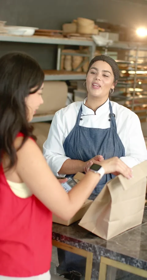 Female customer showing QR code while female baker confirming order, packing box Stock Footage 345130654