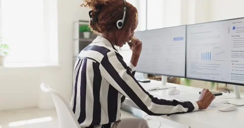 Female customer support agent with headset working at computer in office Stock Footage 337129717