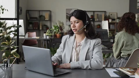 Female Customer Support Agent Talking on Headset at Laptop Stock Footage 343610654