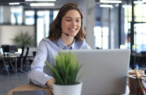 Female customer support operator with headset and smiling. Stock Photos