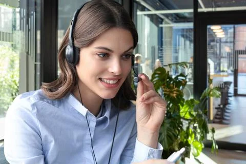 Female customer support operator with headset and smiling, with collegues a.. Stock Photos