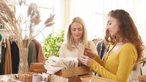 Female customers examining stack of organic clothing and cotton colors. eco Stock Footage 152132784