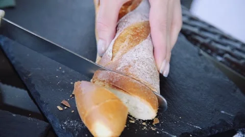 Female cuts the hot fresh bread at the kitchen Stock Footage 63962043
