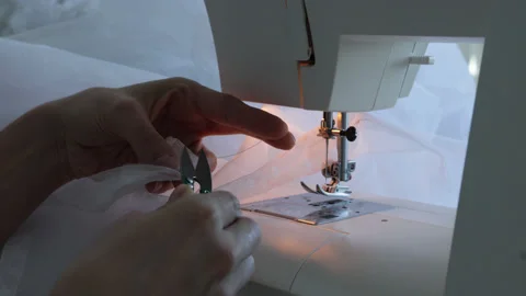 Female cuts thread with scissors on the sewing machine background. Stock Footage 180386119
