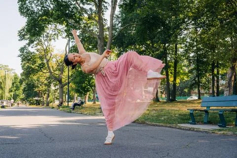 Female dancer gracefully posing, expressing freedom in park Stock Photos