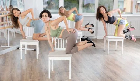 Female dancer in high heels practicing lap dance on chair in studio Stock Photos