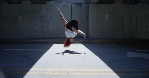 Female dancer performing a front flip under an overpass Stock Footage 97022886