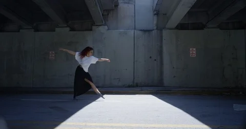 Female dancer performing a front flip under an overpass Stock Footage 97034496