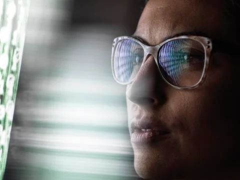 Female data analyst looking at data on screen, reflection in glasses. Foto stock