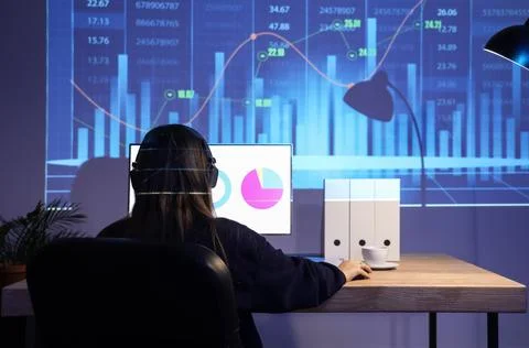 Female data scientist working with computer at desk in dark office, back view Stock Photos