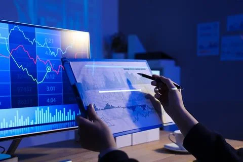 Female data scientist's hands working with diagrams at desk in dark office Stock Photos