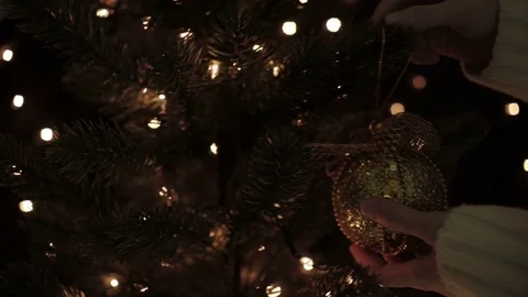 Female decorate on Christmas tree with hanging gold Christmas ball Stock Footage 81410853