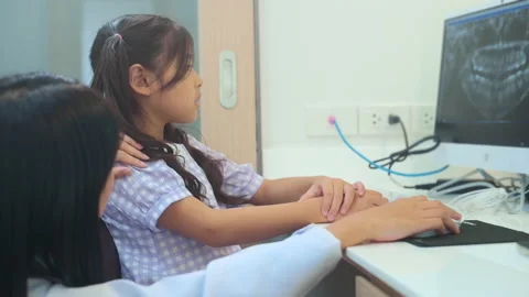 Female dentist explaining teeth x-ray to a little girl in dental clinic, teet Stock Footage 171317062