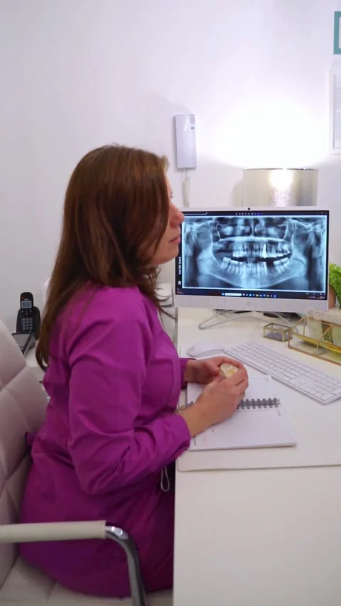 Female dentist explaining an x-ray to her patient in her office. Vertical vid Stock Footage 265565100
