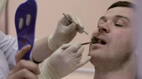 Female dentist showing a tooth with problems to her looking at a mirror patient. Stock Footage 70340820