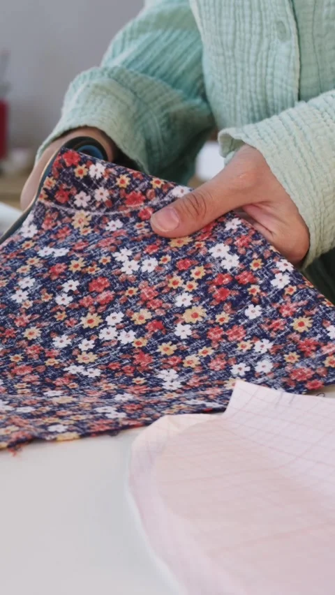 Female designer carving patterns with scissors from floral fabric Stock Footage 330052666