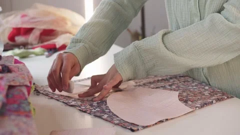Female designer makes marks using paper patterns on floral print fabric Stock Footage 255043971