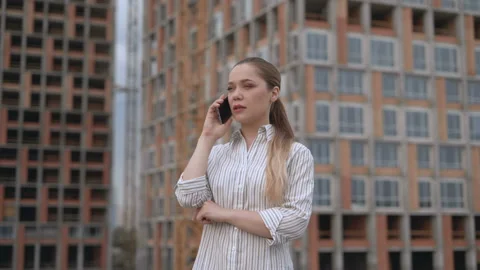 Female designer talking on the phone with a client. location construction. 4K Stock Footage 123468089