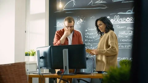 Female Designer Talks with Male Developer, They Look at Personal Computer Screen Stock Footage 82860260