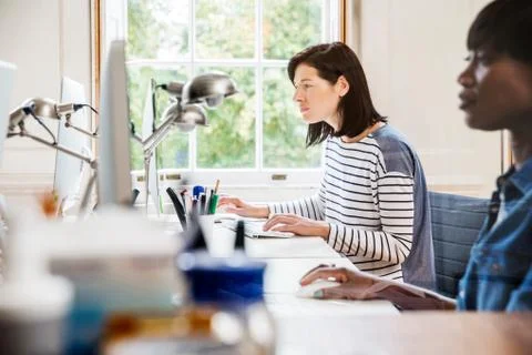 Female designers at desktop computers in creative studio 스톡 사진