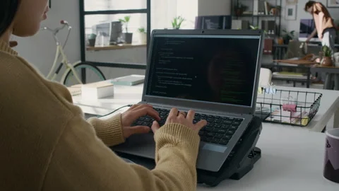 Female Developer Coding on Laptop Placed on Cooling Stand in Modern Office Stock Footage 299207726
