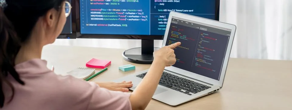 Female developer coding on laptop while computer display program. Burgeoning. Foto stock