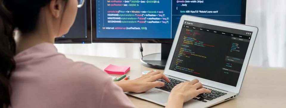 Female developer coding on laptop while computer display program. Burgeoning. 스톡 사진