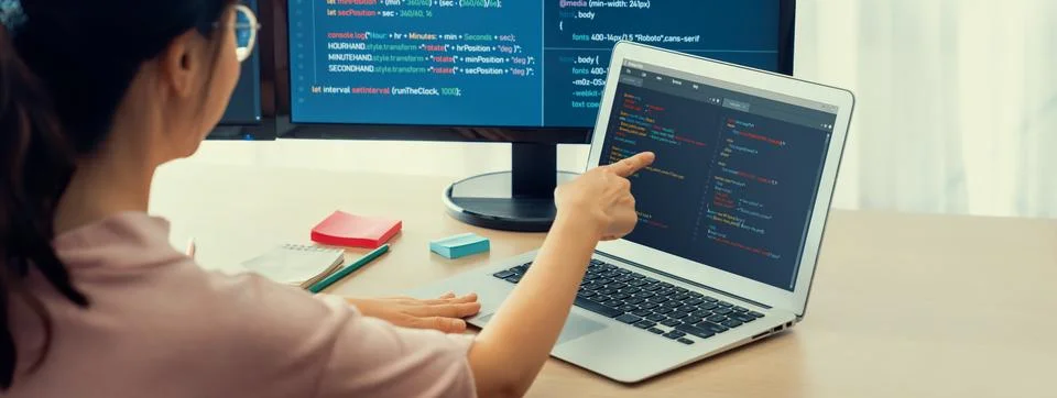 Female developer coding on laptop while computer display program. Burgeoning. 스톡 사진