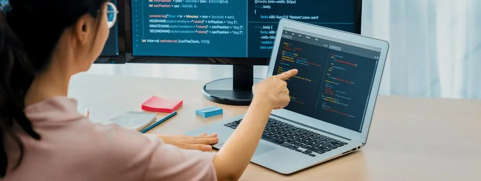Female developer coding on laptop while computer display program. Burgeoning. Foto stock