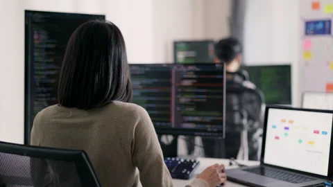 A female developer is observed from behind, scrutinizing a complex codebase. Stock Footage 310589125