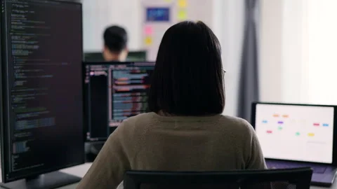 A female developer is observed from behind, scrutinizing a complex codebase. Stock Footage 310589134