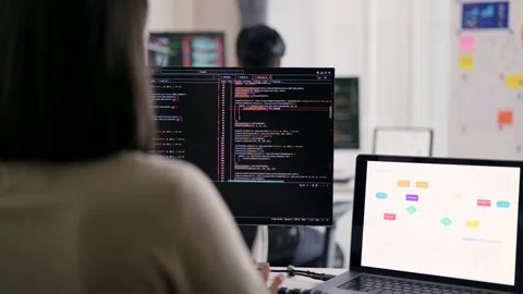 A female developer is observed from behind, scrutinizing a complex codebase. Video stock 310589136