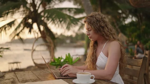 Female developer working on laptop creating apps by the ocean. Young woman Stock Footage 242970621